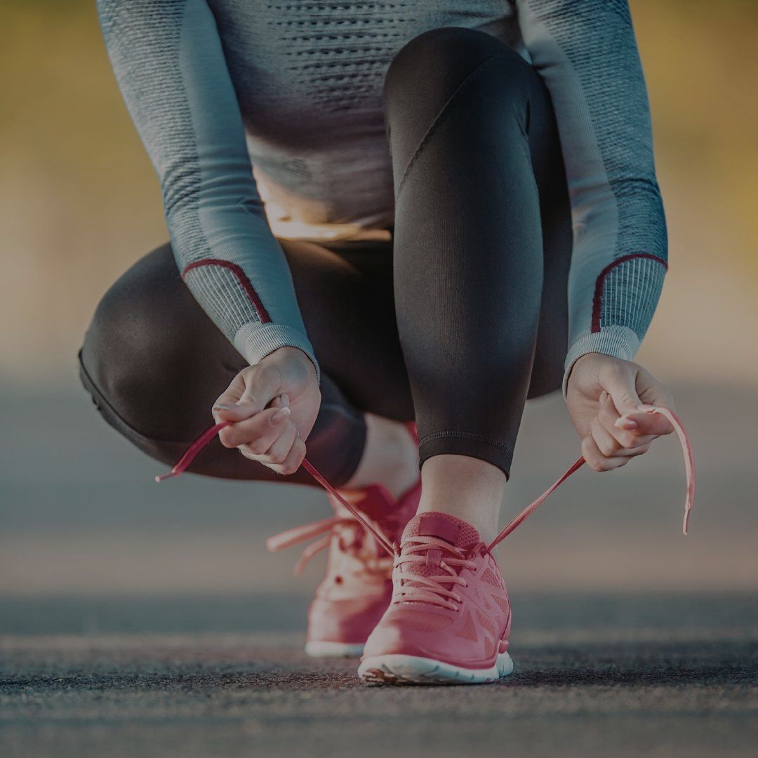 Person tying running shoes on a road with a blurred background
