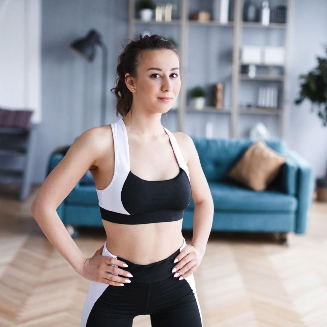 Woman in athletic wear standing in a living room.